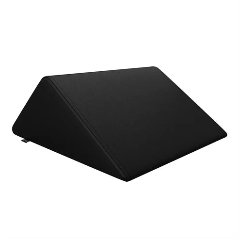DIR black triangular foam bolster pillow providing leg and back support on a massage bed.